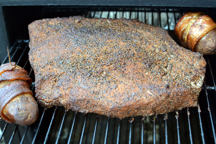 Pastrami cooking on the smoker with potatoes
