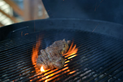 New York Strip being grilled over open flames